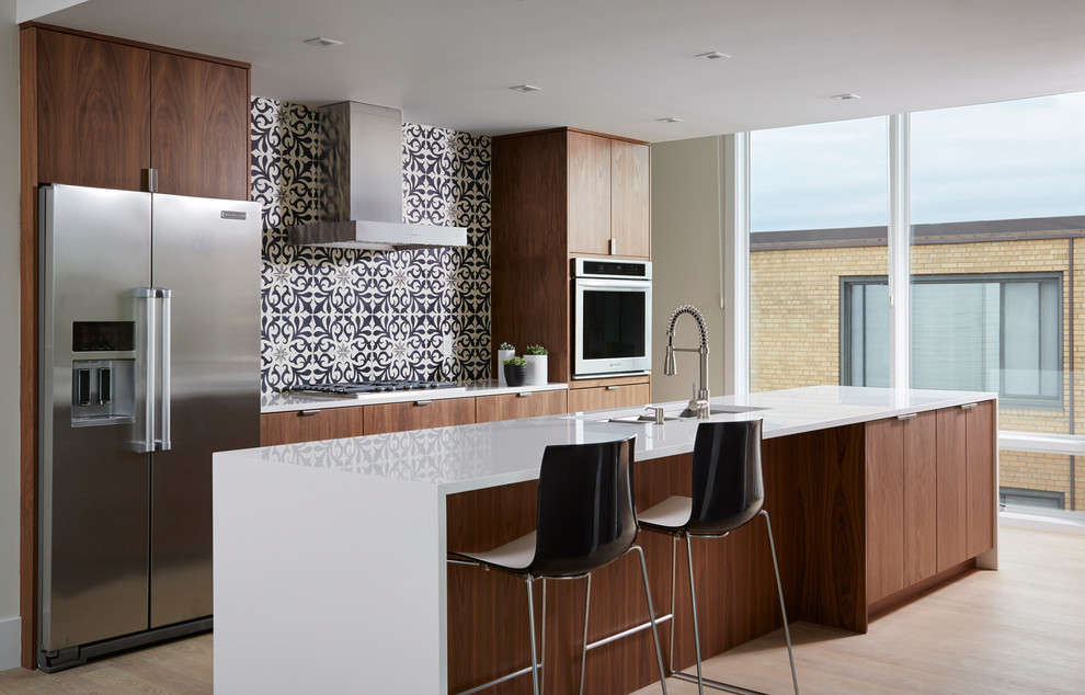 Moderne Küche mit Unterbauwaschbecken, flächenbündigen Schrankfronten, bunter Rückwand, Rückwand aus Zementfliesen, Küchengeräten aus Edelstahl, hellem Holzboden und Kücheninsel in Minneapolis