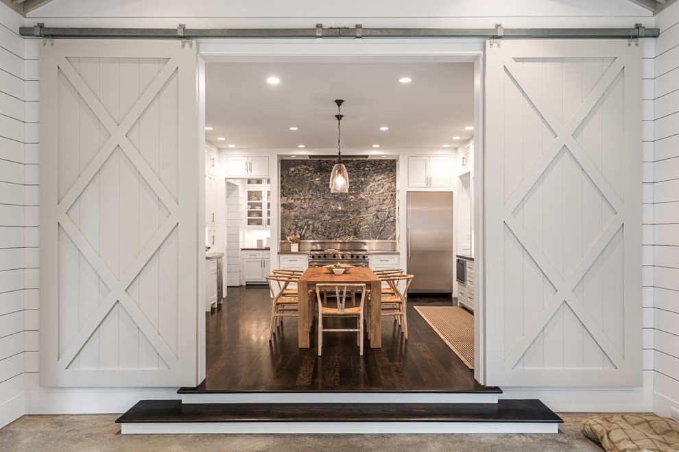 Large farmhouse u-shaped kitchen/diner in Houston with shaker cabinets, white cabinets, grey splashback, stainless steel appliances, dark hardwood flooring, brown floors and an island.