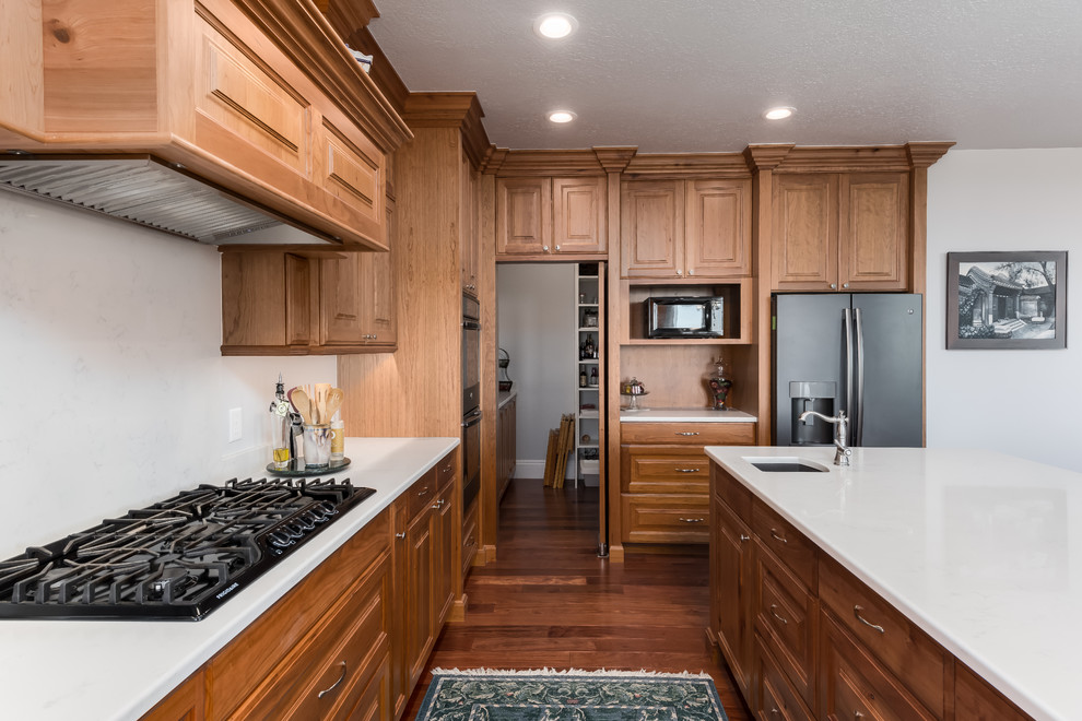 Inspiration for a mid-sized timeless u-shaped medium tone wood floor eat-in kitchen remodel in Salt Lake City with an undermount sink, raised-panel cabinets, light wood cabinets, quartz countertops, white backsplash, stainless steel appliances, an island and white countertops