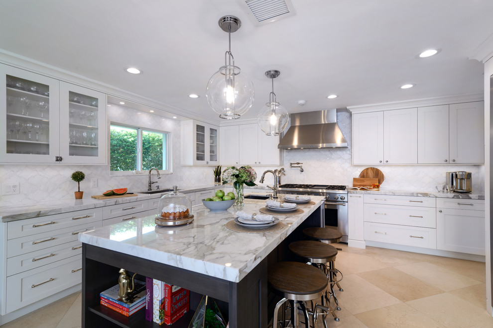 Photo of a traditional l-shaped kitchen in Miami with a submerged sink, shaker cabinets, white cabinets, white splashback, stainless steel appliances, an island, beige floors and white worktops.