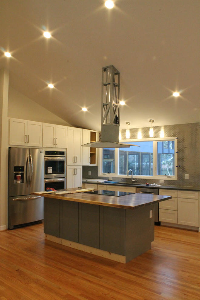 Exempel på ett mellanstort modernt kök, med en undermonterad diskho, skåp i shakerstil, vita skåp, granitbänkskiva, rostfria vitvaror, ljust trägolv och en köksö