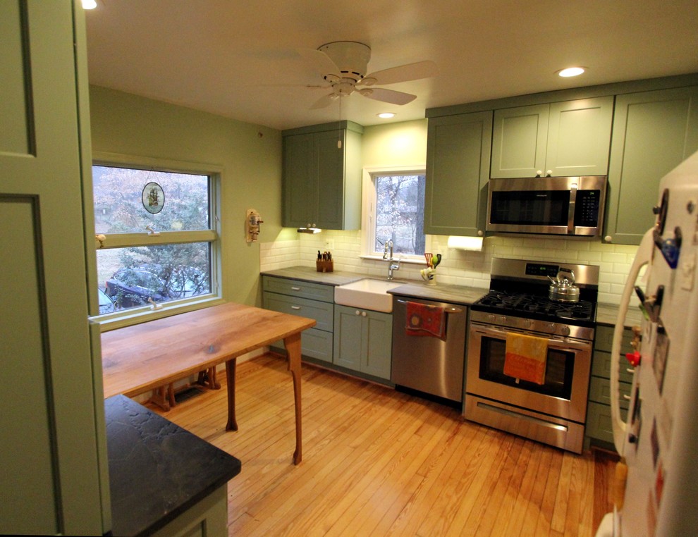 ワシントンD.C.にあるお手頃価格の小さなトラディショナルスタイルのおしゃれなキッチン (エプロンフロントシンク、フラットパネル扉のキャビネット、緑のキャビネット、珪岩カウンター、白いキッチンパネル、磁器タイルのキッチンパネル、シルバーの調理設備、淡色無垢フローリング、アイランドなし、オレンジの床) の写真