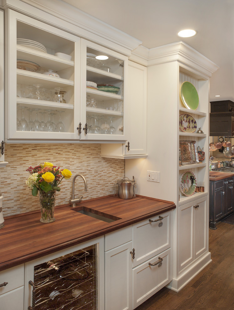 Example of a large classic galley dark wood floor and brown floor eat-in kitchen design in New York with an undermount sink, beaded inset cabinets, white cabinets, wood countertops, multicolored backsplash, glass sheet backsplash, paneled appliances, an island and brown countertops