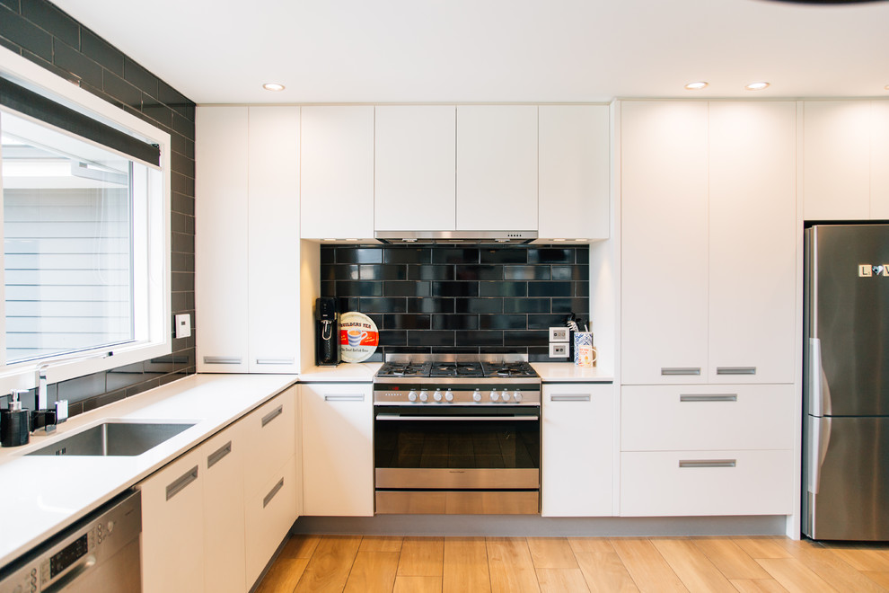 Mittelgroße Moderne Wohnküche in U-Form mit Unterbauwaschbecken, Küchenrückwand in Schwarz, Rückwand aus Metrofliesen, Küchengeräten aus Edelstahl und Kücheninsel in Christchurch