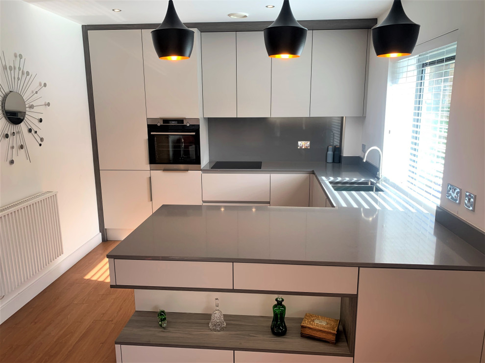 Photo of a small contemporary u-shaped open plan kitchen in Other with a single-bowl sink, flat-panel cabinets, dark wood cabinets, composite countertops, grey splashback, black appliances, vinyl flooring and grey worktops.