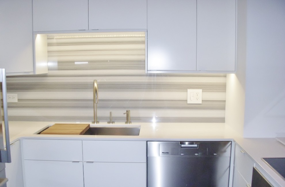 This is an example of a small modern u-shaped open plan kitchen in Chicago with a submerged sink, flat-panel cabinets, white cabinets, engineered stone countertops, grey splashback, stainless steel appliances and no island.