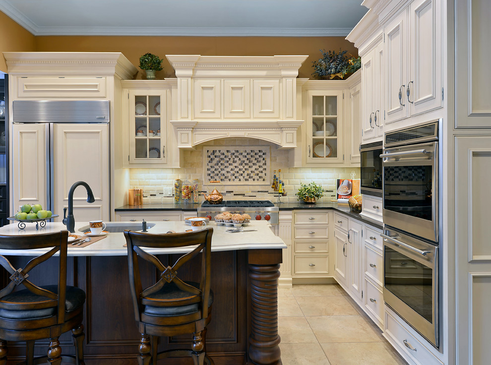 Klassisk inredning av ett kök, med vita skåp, en köksö, en enkel diskho, luckor med infälld panel, bänkskiva i kvarts och integrerade vitvaror