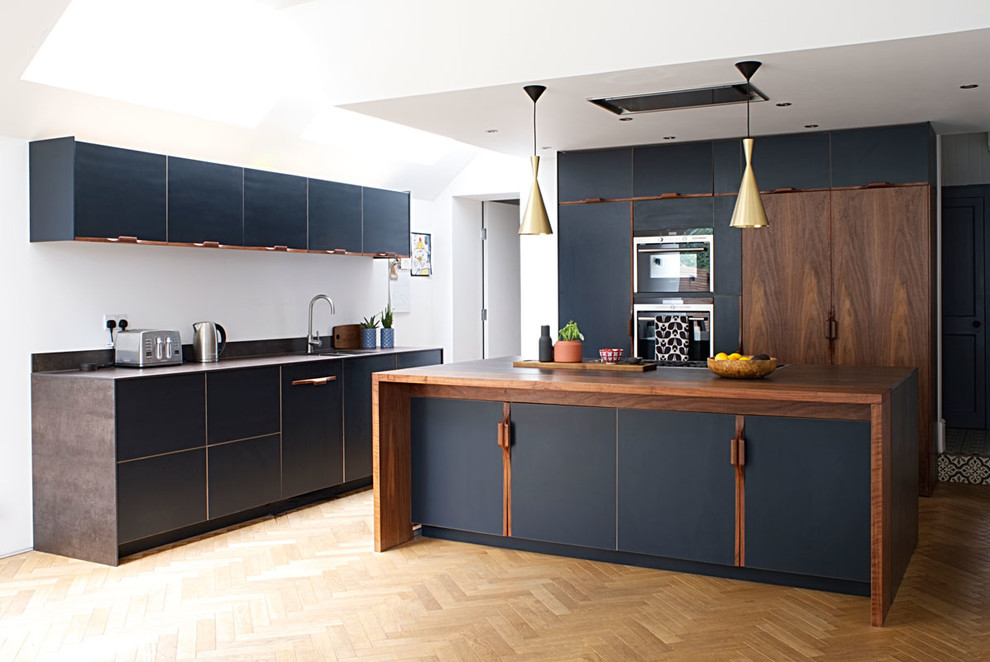 Foto på ett mellanstort funkis brun kök, med en dubbel diskho, släta luckor, blå skåp, träbänkskiva, rostfria vitvaror, ljust trägolv, en köksö och brunt golv
