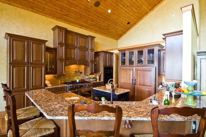 Eat-in kitchen - huge traditional u-shaped light wood floor eat-in kitchen idea in Charlotte with an undermount sink, raised-panel cabinets, medium tone wood cabinets, granite countertops, beige backsplash, stone tile backsplash, stainless steel appliances and an island