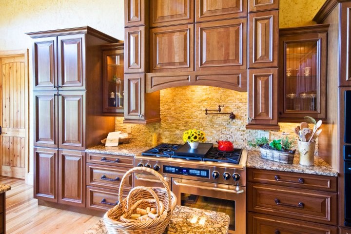 Inredning av ett klassiskt mycket stort kök, med luckor med upphöjd panel, skåp i mellenmörkt trä, granitbänkskiva, beige stänkskydd, stänkskydd i stenkakel, rostfria vitvaror, ljust trägolv, en köksö och en undermonterad diskho