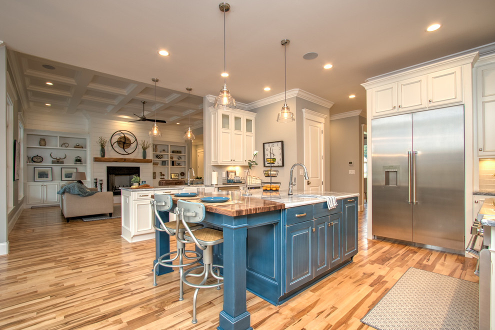 Kitchen pantry - large transitional u-shaped light wood floor and multicolored floor kitchen pantry idea in Other with a farmhouse sink, raised-panel cabinets, white cabinets, quartzite countertops, gray backsplash, glass tile backsplash, stainless steel appliances and an island