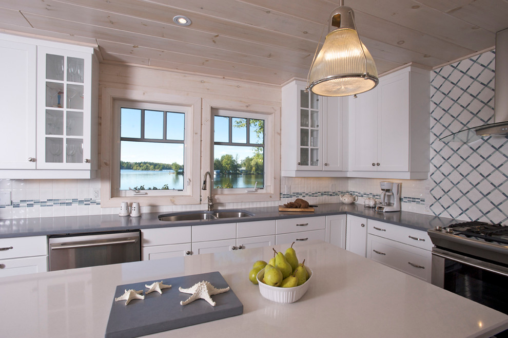 Foto di una cucina costiera con lavello sottopiano, ante con riquadro incassato, ante bianche, paraspruzzi bianco e elettrodomestici in acciaio inossidabile