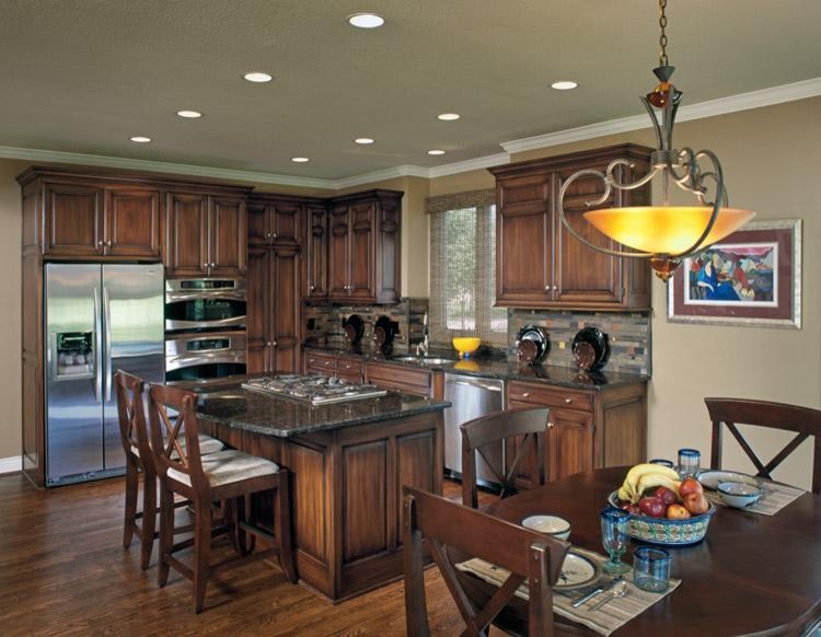 Example of a small classic l-shaped medium tone wood floor eat-in kitchen design in Kansas City with a double-bowl sink, beaded inset cabinets, medium tone wood cabinets, granite countertops, multicolored backsplash, stone tile backsplash, stainless steel appliances and an island