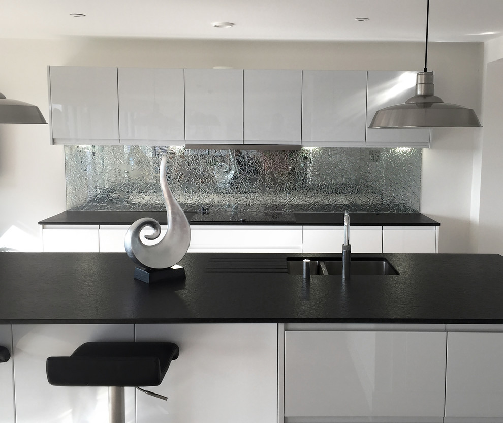 Photo of a large contemporary kitchen in Hertfordshire with glass sheet splashback.