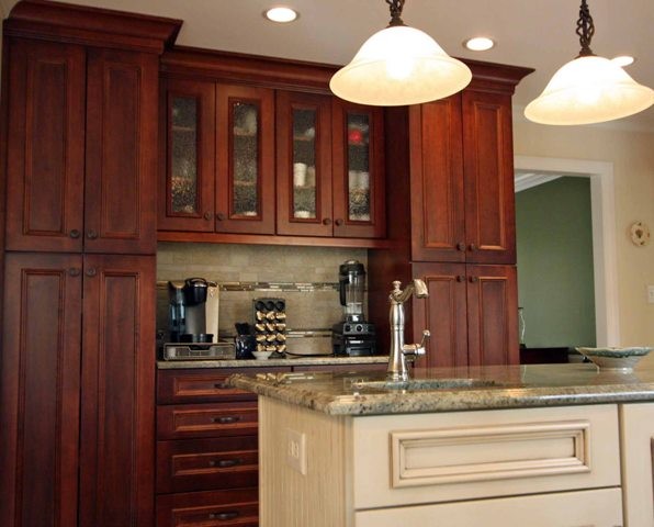 Klassisk inredning av ett kök, med en undermonterad diskho, luckor med infälld panel, skåp i mörkt trä, granitbänkskiva, grönt stänkskydd, stänkskydd i porslinskakel och rostfria vitvaror