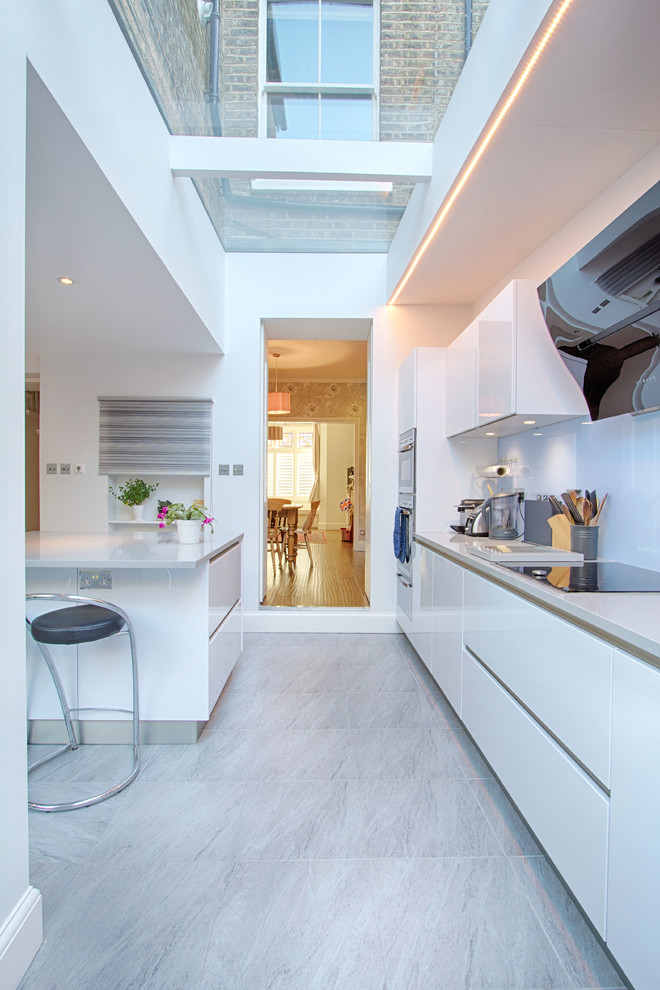 Moderne Küche mit flächenbündigen Schrankfronten, weißen Schränken und Küchenrückwand in Weiß in London