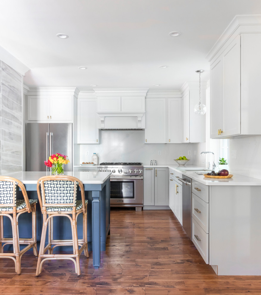 Klassische Küche in L-Form mit Unterbauwaschbecken, Schrankfronten im Shaker-Stil, weißen Schränken, Küchengeräten aus Edelstahl, dunklem Holzboden, Kücheninsel, braunem Boden und weißer Arbeitsplatte in Boston