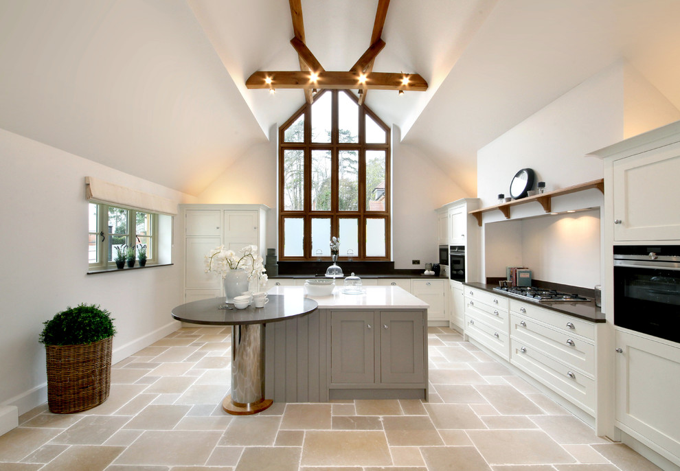 Modern inredning av ett stort kök, med skåp i shakerstil, granitbänkskiva, svarta vitvaror, travertin golv och en köksö