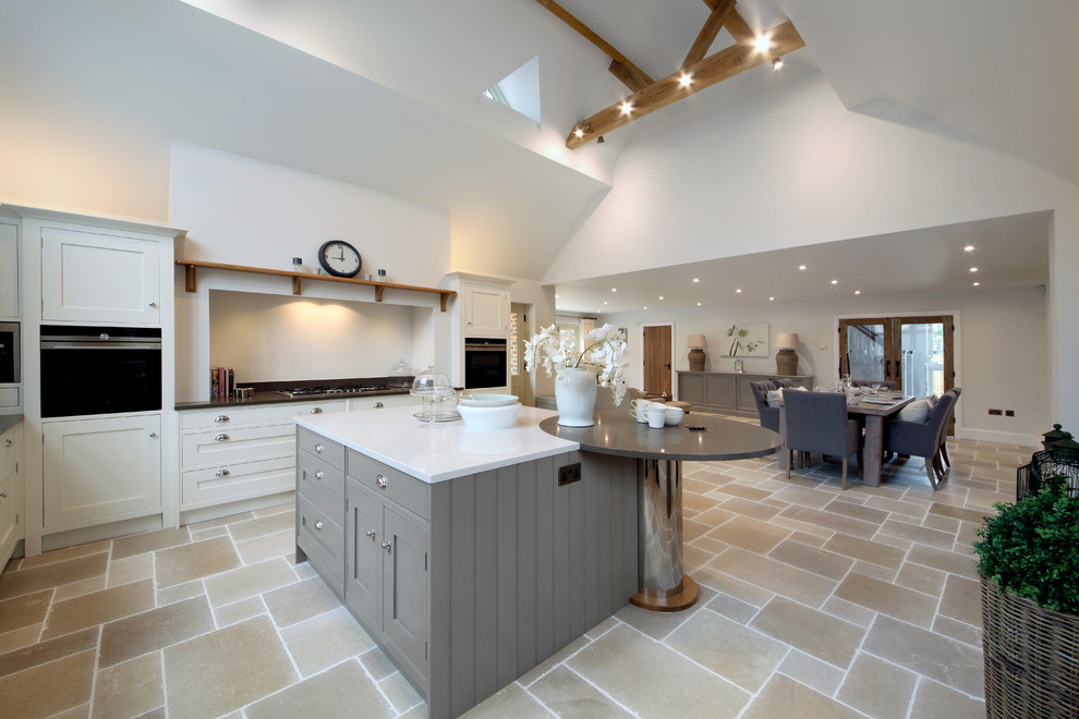 Foto på ett stort funkis kök, med skåp i shakerstil, granitbänkskiva, svarta vitvaror, travertin golv och en köksö