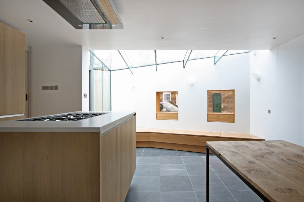 Mittelgroße Moderne Wohnküche in L-Form mit flächenbündigen Schrankfronten, hellen Holzschränken, Schieferboden und Kücheninsel in Devon