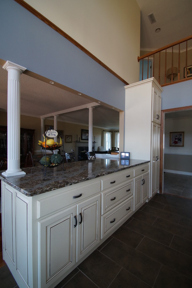 Foto på ett mellanstort vintage blå kök, med en undermonterad diskho, luckor med upphöjd panel, vita skåp, bänkskiva i kvarts, brunt stänkskydd, stänkskydd i tunnelbanekakel, rostfria vitvaror, klinkergolv i porslin, en köksö och brunt golv