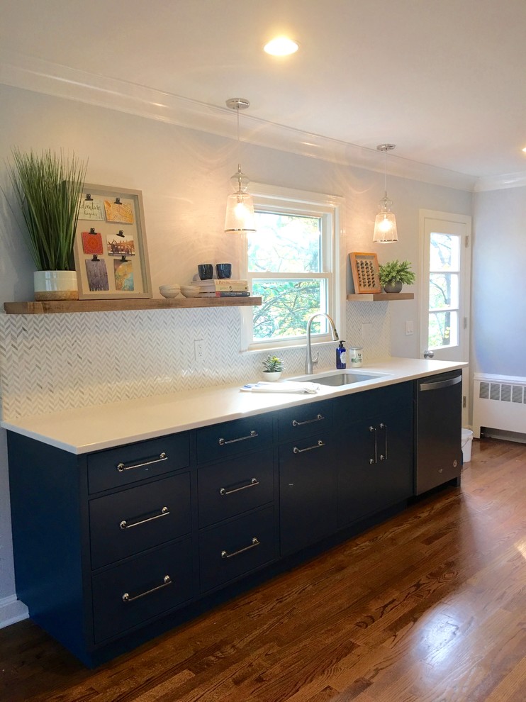 Transitional galley medium tone wood floor and brown floor kitchen photo in New York with a single-bowl sink, flat-panel cabinets, blue cabinets, solid surface countertops, multicolored backsplash, mosaic tile backsplash and stainless steel appliances