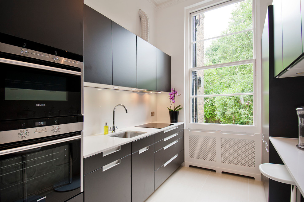 Zweizeilige Moderne Küche ohne Insel mit Unterbauwaschbecken, flächenbündigen Schrankfronten und schwarzen Elektrogeräten in London