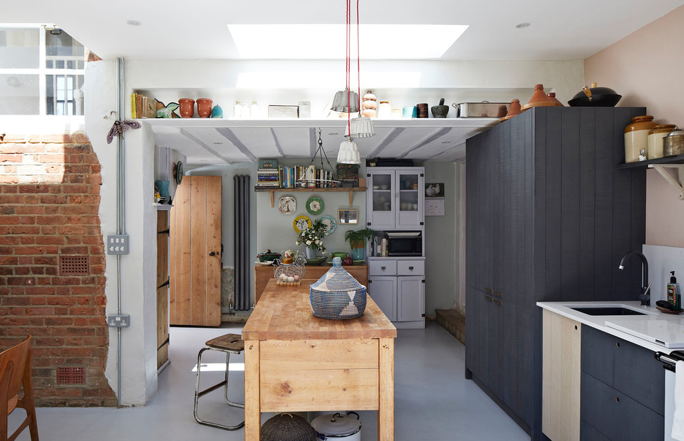 Inredning av ett lantligt mellanstort vit linjärt vitt kök, med en undermonterad diskho, släta luckor, blå skåp, vitt stänkskydd, en köksö och grått golv