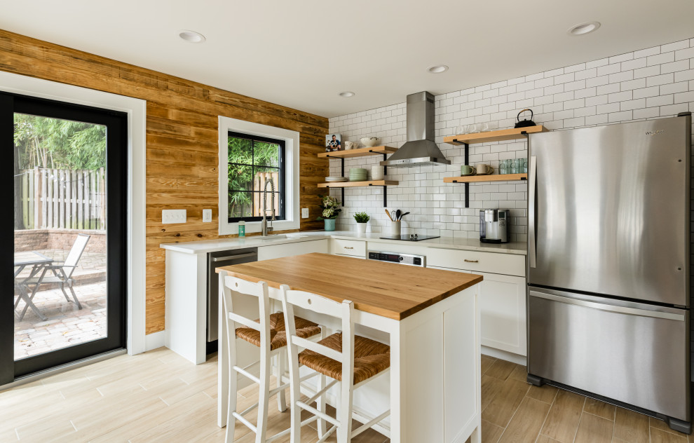 Design ideas for a medium sized farmhouse l-shaped kitchen in DC Metro with shaker cabinets, white cabinets, wood worktops, white splashback, metro tiled splashback, stainless steel appliances, an island, brown worktops, a submerged sink and beige floors.