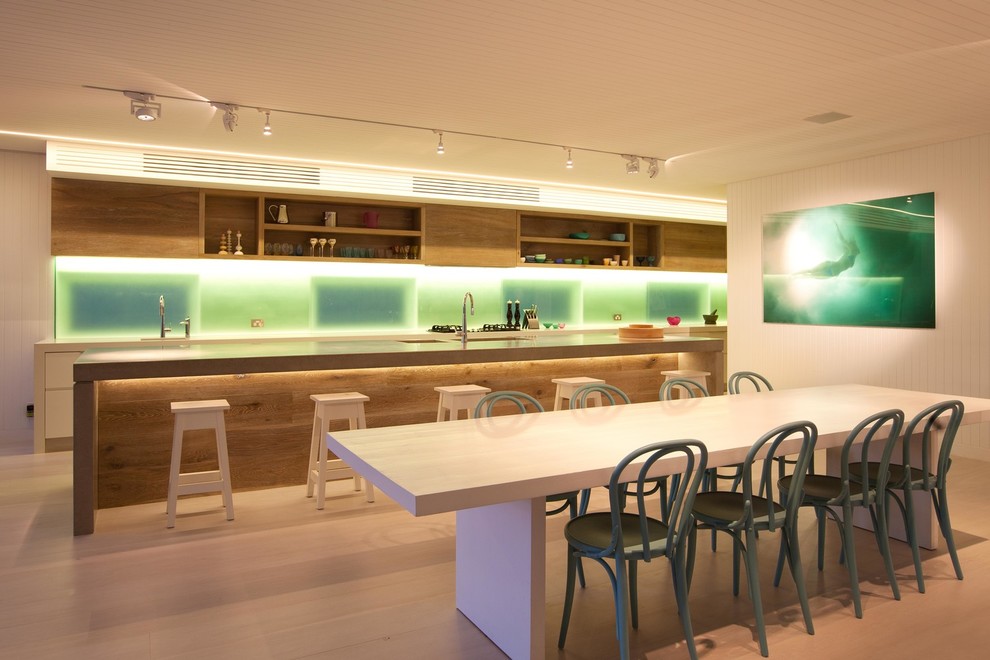 Diseño de cocina comedor contemporánea de tamaño medio con armarios con paneles lisos, puertas de armario de madera clara, suelo de madera clara y una isla