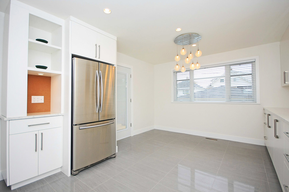 Large minimalist l-shaped porcelain tile kitchen photo in Vancouver with an undermount sink, flat-panel cabinets, white cabinets, quartz countertops, white backsplash and stainless steel appliances
