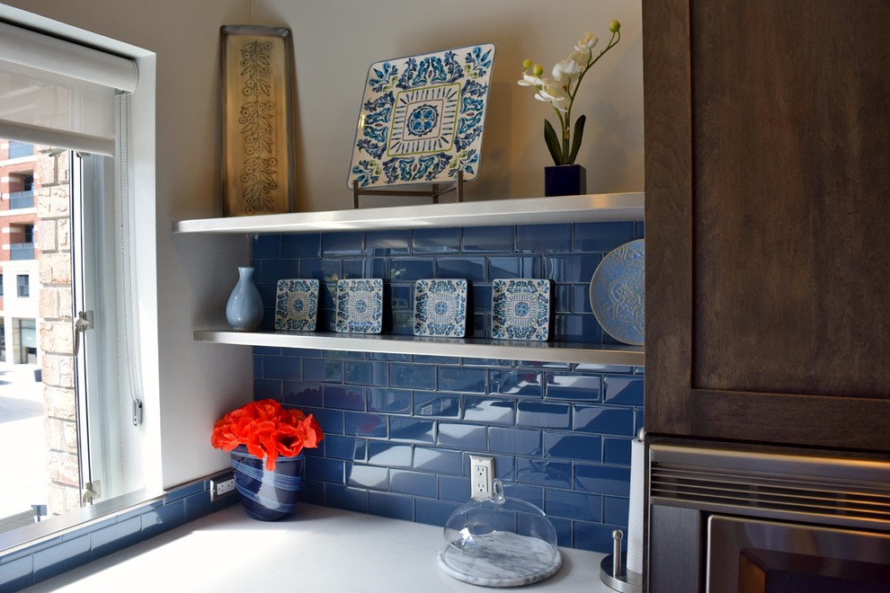 Modern inredning av ett kök, med en undermonterad diskho, luckor med infälld panel, bruna skåp, bänkskiva i kvarts, blått stänkskydd, stänkskydd i porslinskakel, rostfria vitvaror, mörkt trägolv och en halv köksö