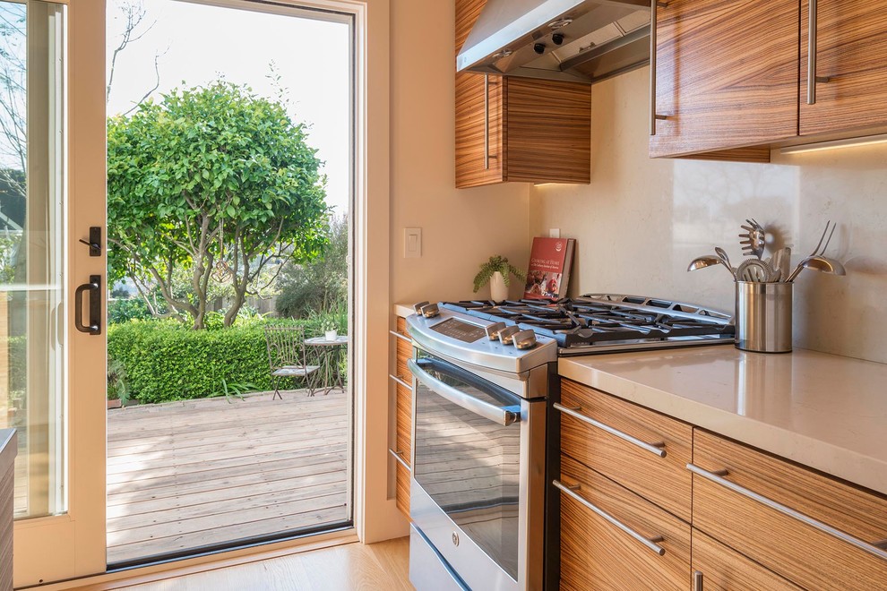 Small minimalist l-shaped light wood floor and brown floor enclosed kitchen photo in San Francisco with an undermount sink, flat-panel cabinets, medium tone wood cabinets, quartz countertops, white backsplash, stone slab backsplash, stainless steel appliances, no island and yellow countertops