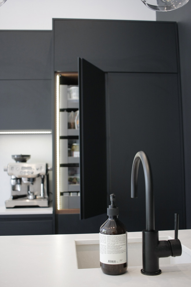 Design ideas for a small contemporary galley open plan kitchen in London with flat-panel cabinets, black cabinets, quartz worktops, white splashback, an island and white worktops.
