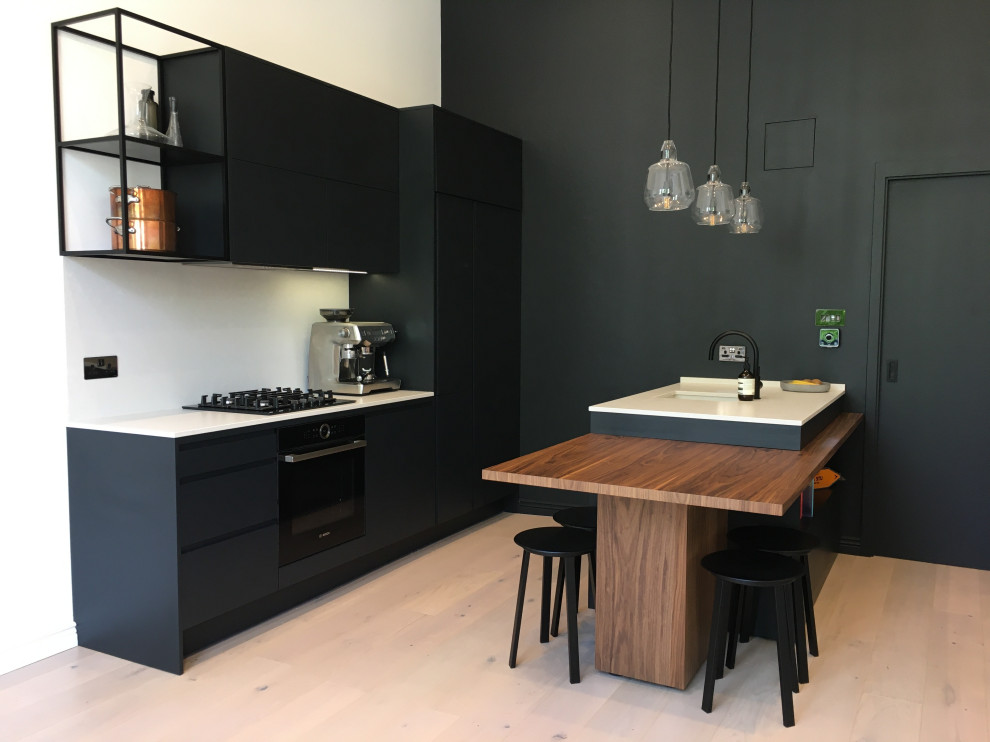 Design ideas for a small contemporary galley open plan kitchen in London with flat-panel cabinets, black cabinets, quartz worktops, white splashback, an island and white worktops.