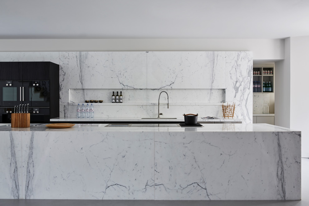 Inspiration for a large contemporary kitchen remodel in London with marble countertops, marble backsplash, an island, an undermount sink and black appliances