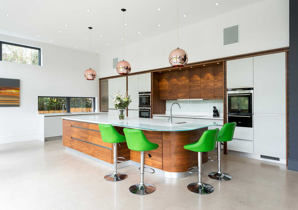 Example of a trendy kitchen design in Kent with an undermount sink, flat-panel cabinets, white cabinets, white backsplash, black appliances and an island