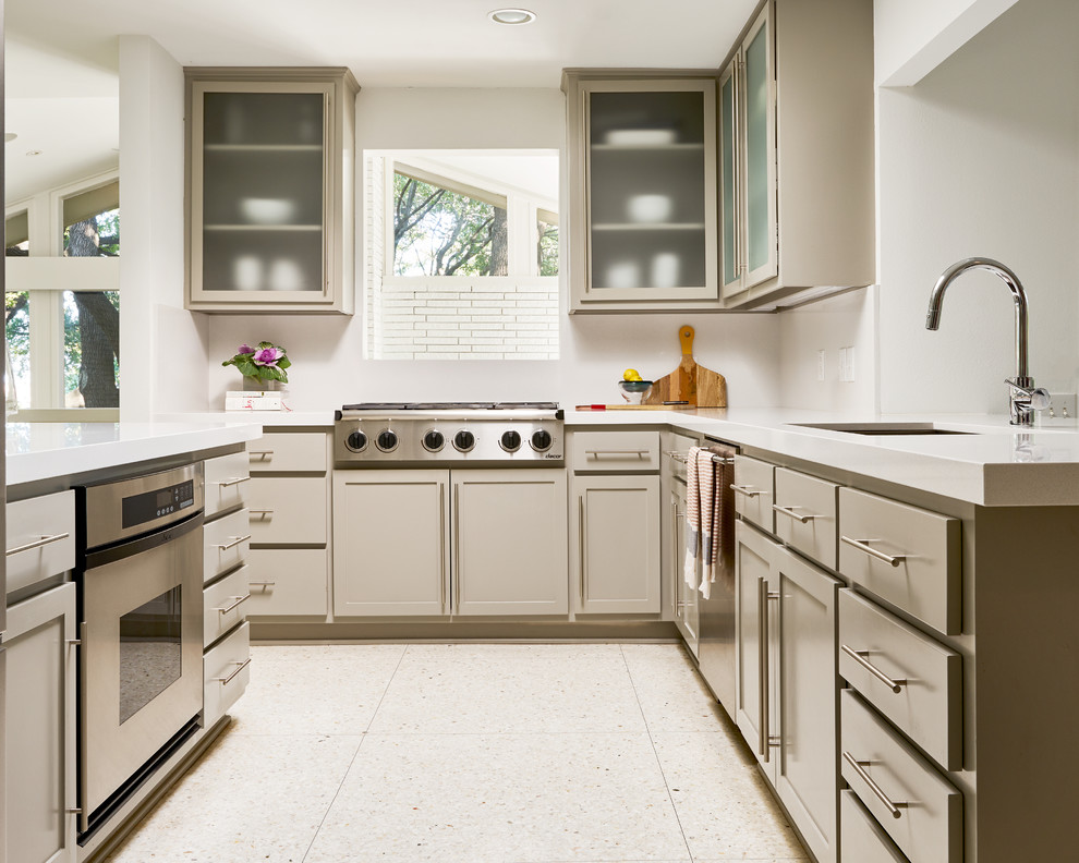 Ispirazione per una cucina abitabile minimalista di medie dimensioni con lavello da incasso, ante di vetro, ante bianche, paraspruzzi bianco e elettrodomestici in acciaio inossidabile