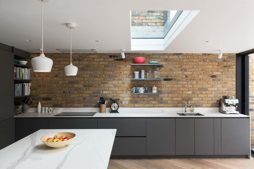 Foto de cocina contemporánea de tamaño medio con fregadero bajoencimera, armarios con paneles lisos, puertas de armario grises, encimera de mármol, una isla y salpicadero de ladrillos