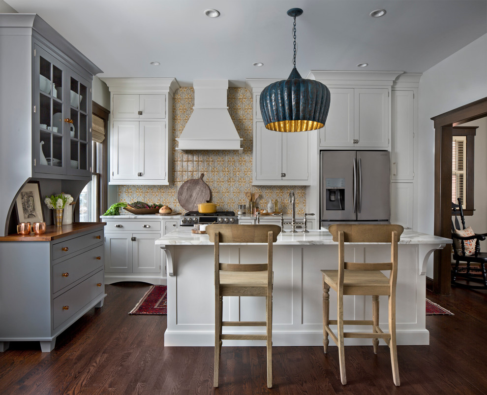 Réalisation d'une cuisine tradition avec un placard à porte shaker, des portes de placard blanches, une crédence multicolore, un électroménager en acier inoxydable, parquet foncé et îlot.