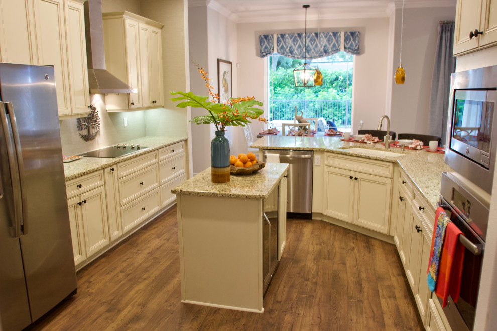 Inspiration for a coastal galley laminate floor and brown floor eat-in kitchen remodel in Other with an undermount sink, recessed-panel cabinets, white cabinets, granite countertops, beige backsplash, stainless steel appliances, an island and beige countertops