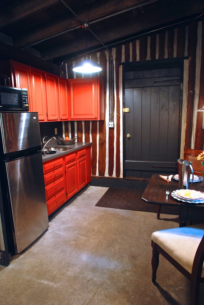 Exemple d'une petite cuisine ouverte linéaire montagne avec un évier posé, un placard avec porte à panneau surélevé, des portes de placard rouges, un plan de travail en stratifié, un électroménager en acier inoxydable, un sol en contreplaqué et aucun îlot.