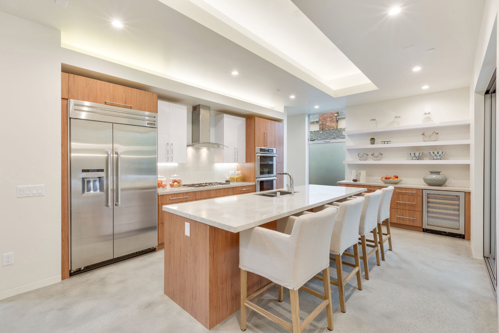 Foto di una cucina minimal di medie dimensioni con lavello sottopiano, ante lisce, ante in legno scuro, paraspruzzi bianco e elettrodomestici in acciaio inossidabile