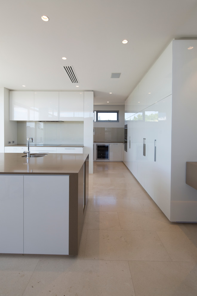 Contemporary kitchen/diner in Perth with a submerged sink, flat-panel cabinets, white cabinets, white splashback, glass sheet splashback, stainless steel appliances, an island, composite countertops and ceramic flooring.