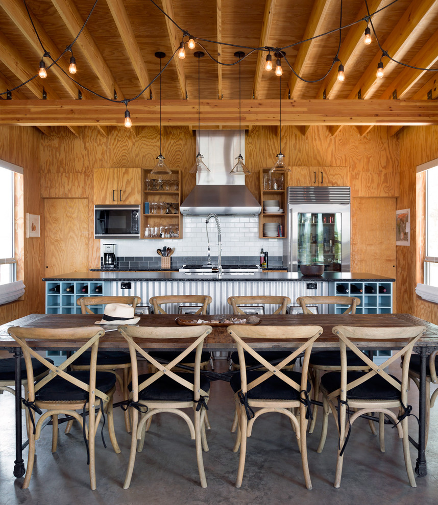 Zweizeilige Industrial Wohnküche mit Küchenrückwand in Weiß, Rückwand aus Metrofliesen, Küchengeräten aus Edelstahl, Betonboden und Kücheninsel in Austin