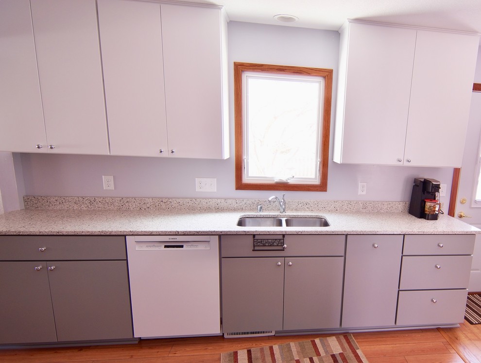 Inredning av ett modernt mellanstort vit vitt kök, med en nedsänkt diskho, släta luckor, vita skåp, bänkskiva i kvarts, vitt stänkskydd, stänkskydd i sten, vita vitvaror, vinylgolv och brunt golv