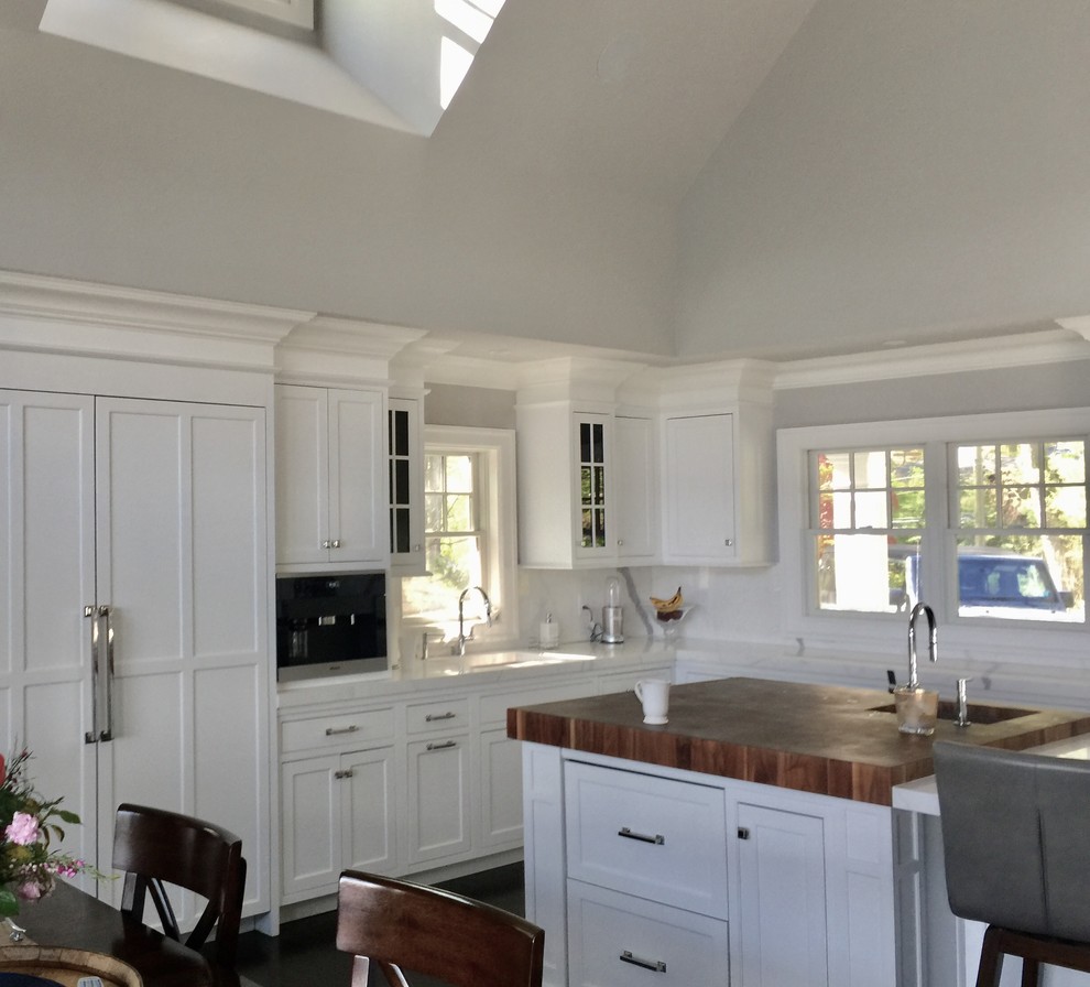 Large transitional u-shaped dark wood floor and brown floor kitchen pantry photo in New York with an undermount sink, flat-panel cabinets, white cabinets, glass countertops, white backsplash, glass sheet backsplash, paneled appliances and an island
