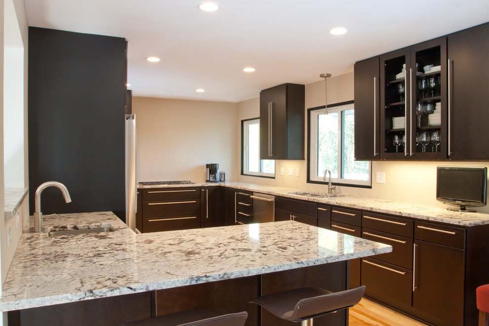 Photo of a medium sized modern u-shaped kitchen/diner in Minneapolis with a submerged sink, flat-panel cabinets, black cabinets, granite worktops, stainless steel appliances, light hardwood flooring and a breakfast bar.