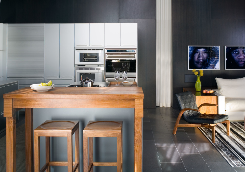 Modelo de cocina actual abierta con armarios con paneles lisos, puertas de armario grises y electrodomésticos de acero inoxidable