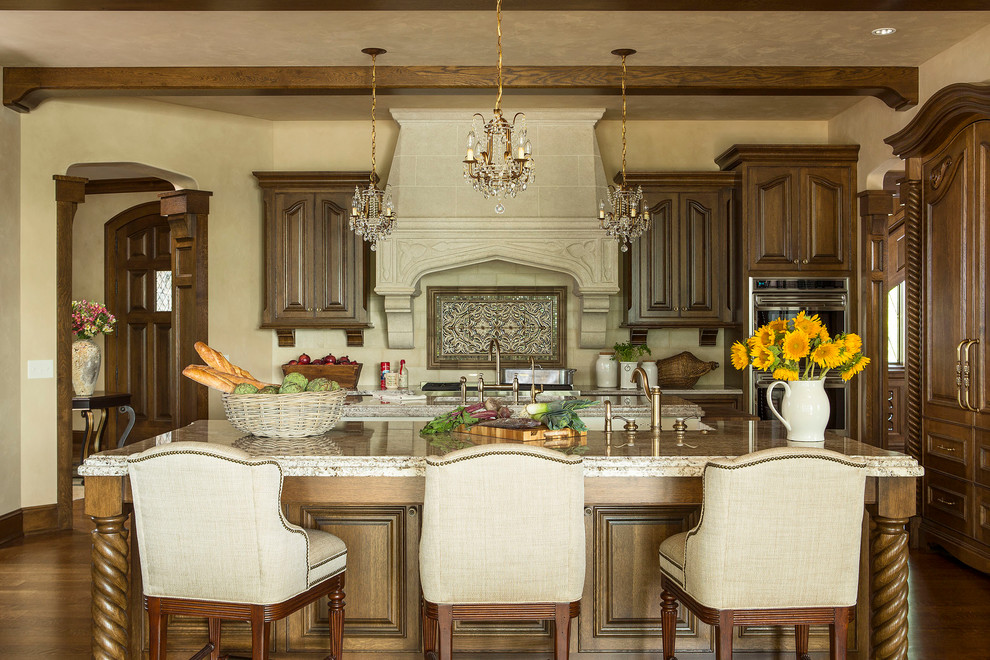 Idée de décoration pour une cuisine américaine encastrable tradition en L et bois brun avec un plan de travail en granite, un évier de ferme et une crédence beige.